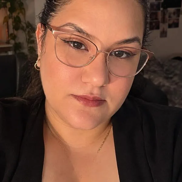Portrait de Tania Zermane : cheveux bruns relevés, lunettes fines, regard posé vers l'objectif.